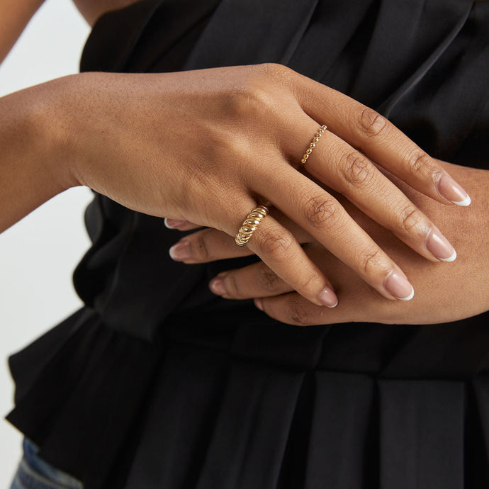 Close-up of a person's hand wearing gold rings on a black top background